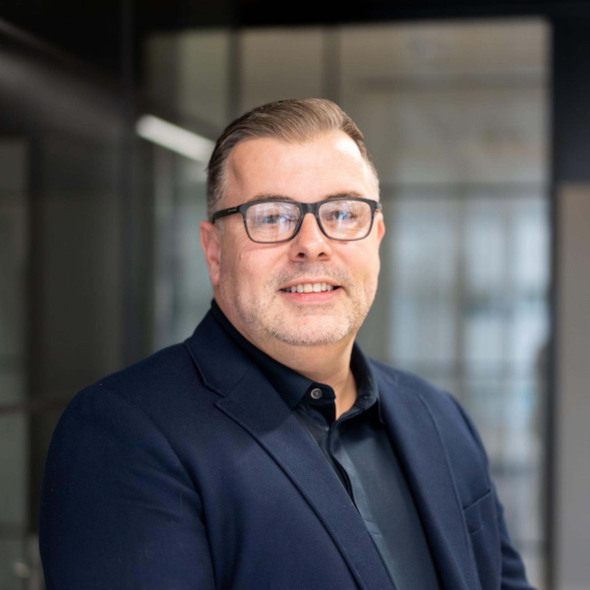 Professional man wearing glasses and a blazer, embodying modern workplace technology and innovation concepts.
