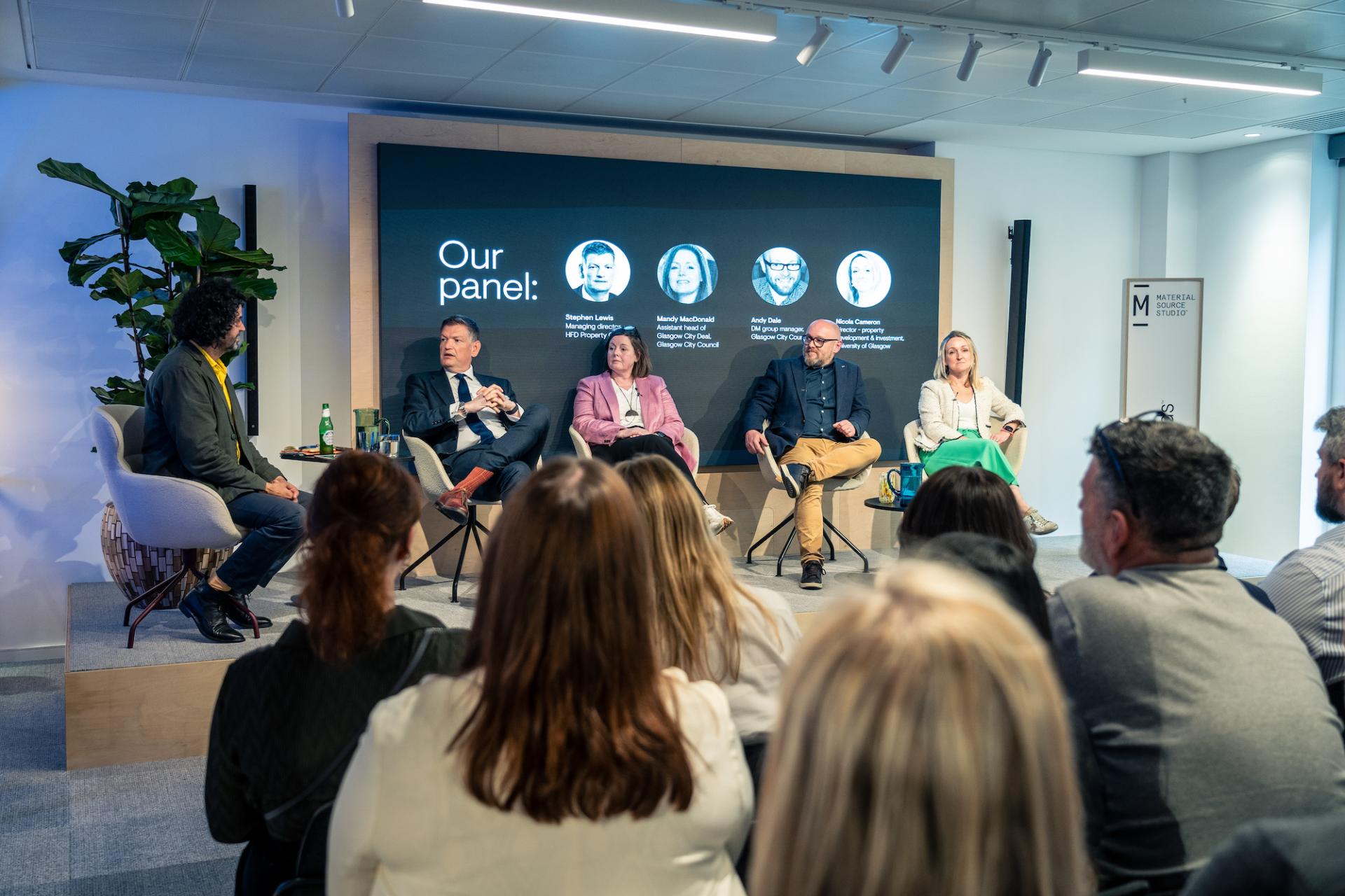 Panel discussion on Glasgow's property outlook featuring experts, with attendees engaged in the background.