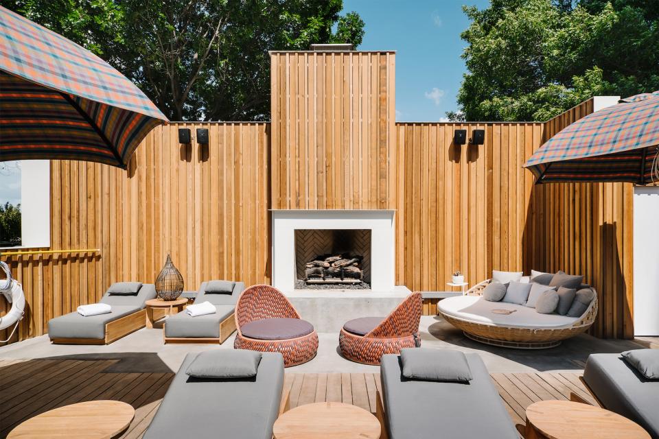 Lounge area of a mid-century hotel in Austin featuring natural wood, modern seating, and a stylish outdoor fireplace.