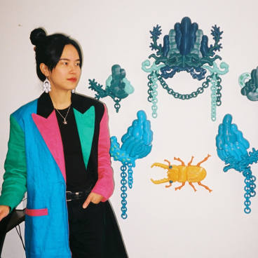Soorin Shin stands beside vibrant 3D art installations, showcasing her unique style and artistic practice in Glasgow.