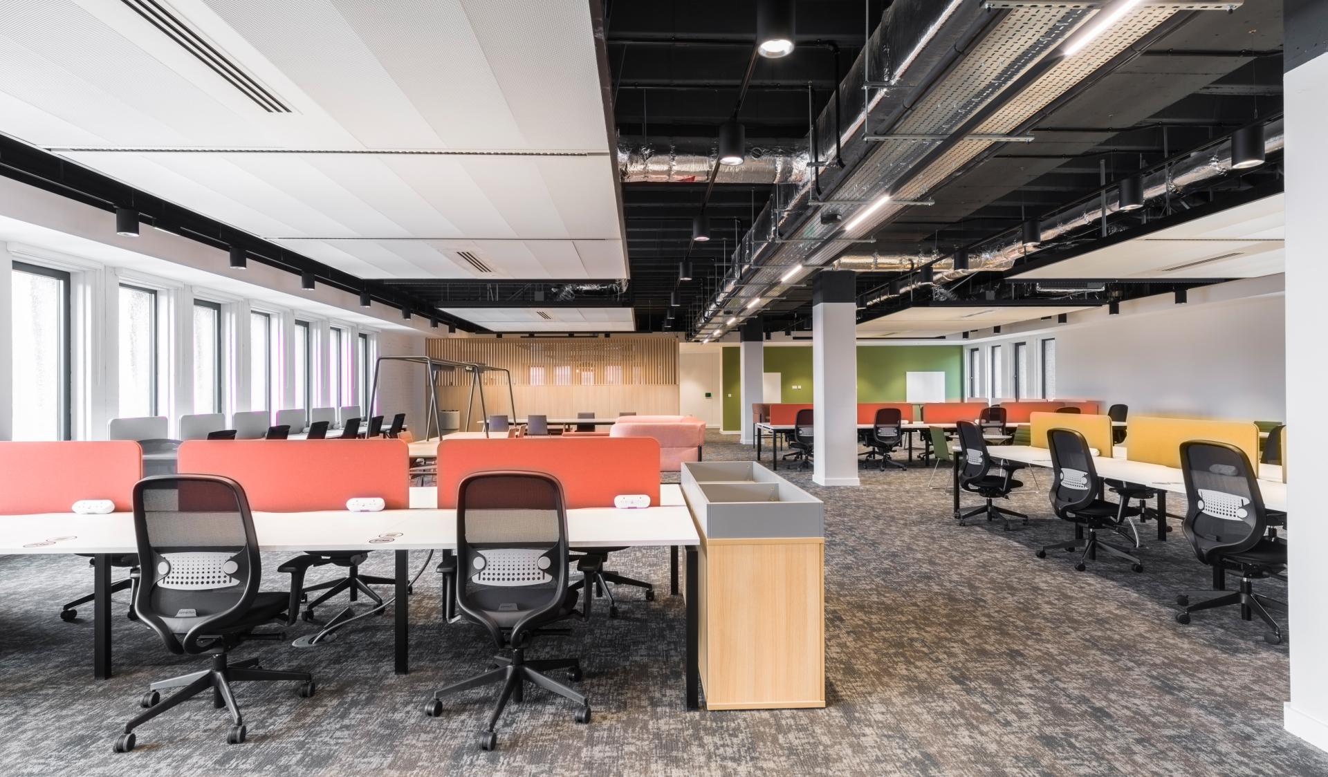 Modern office interior featuring open, collaborative spaces, vibrant seating areas, and stylish desk arrangements designed by SpaceInvader.