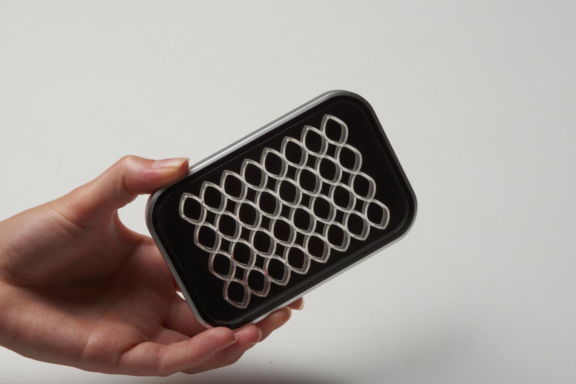 Hand holding a patterned CMF material sample, showcasing innovative design in sustainable luxury applications.