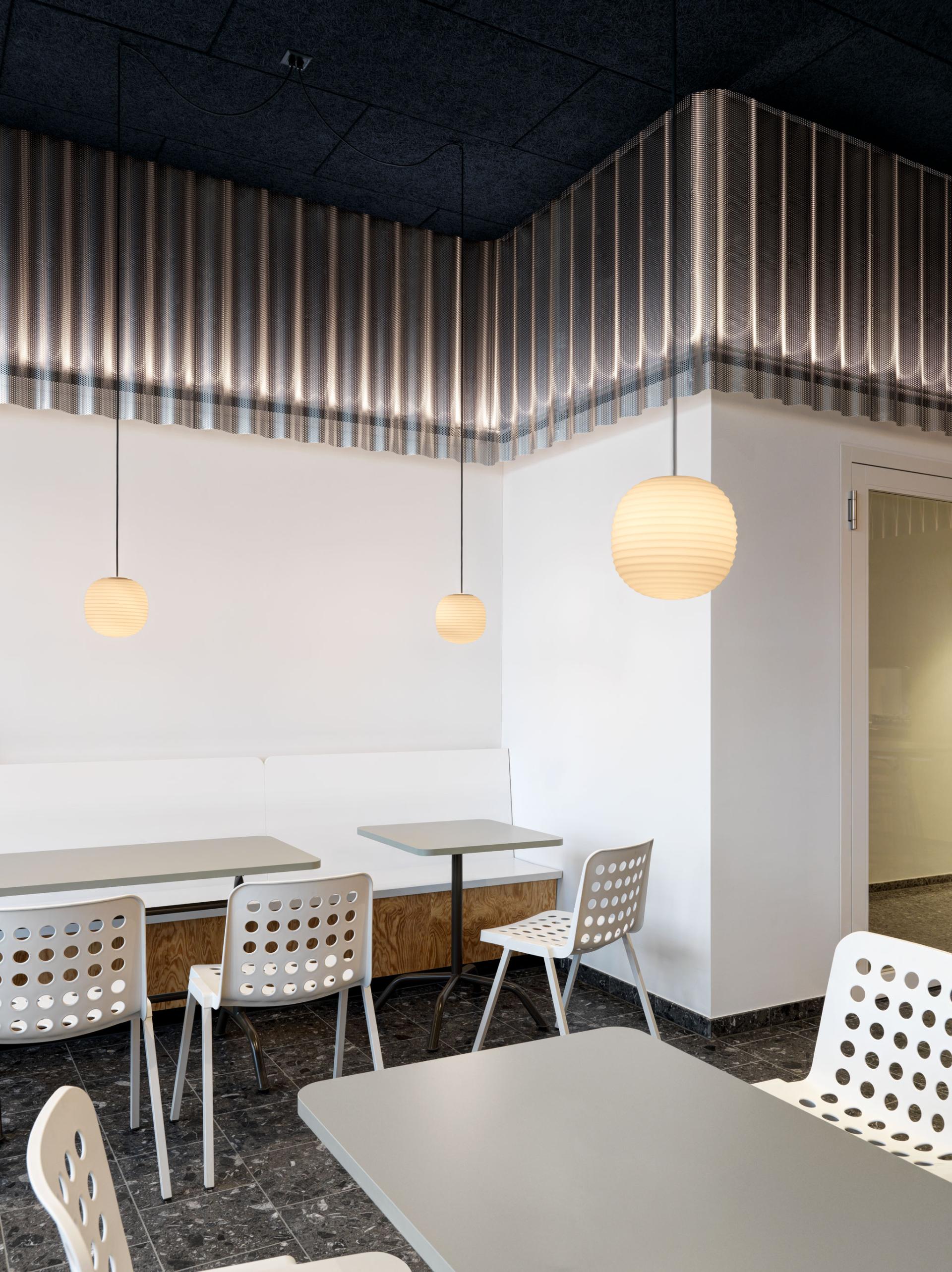 Modern cafe interior featuring minimalist design, stylish pendant lights, and contemporary seating by Studio Gessaga for Ferrum AG.