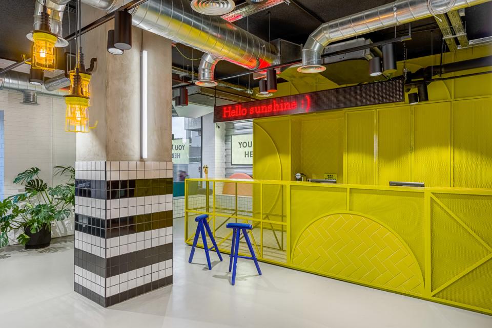 Vibrant reception area of The Student Hotel in Barcelona, featuring yellow accents and modern co-working design elements.