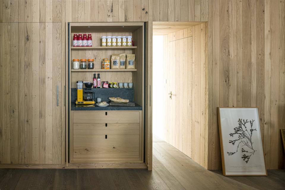 Modern kitchen storage unit featuring wood, Caesarstone countertop, coffee maker, and neatly organized jars and containers.