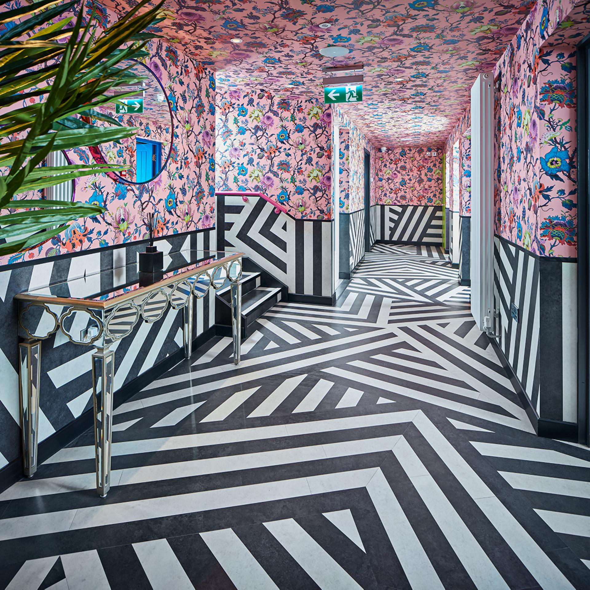 Luxurious vinyl flooring featuring bold black and white geometric patterns in a vibrant, floral-themed corridor.