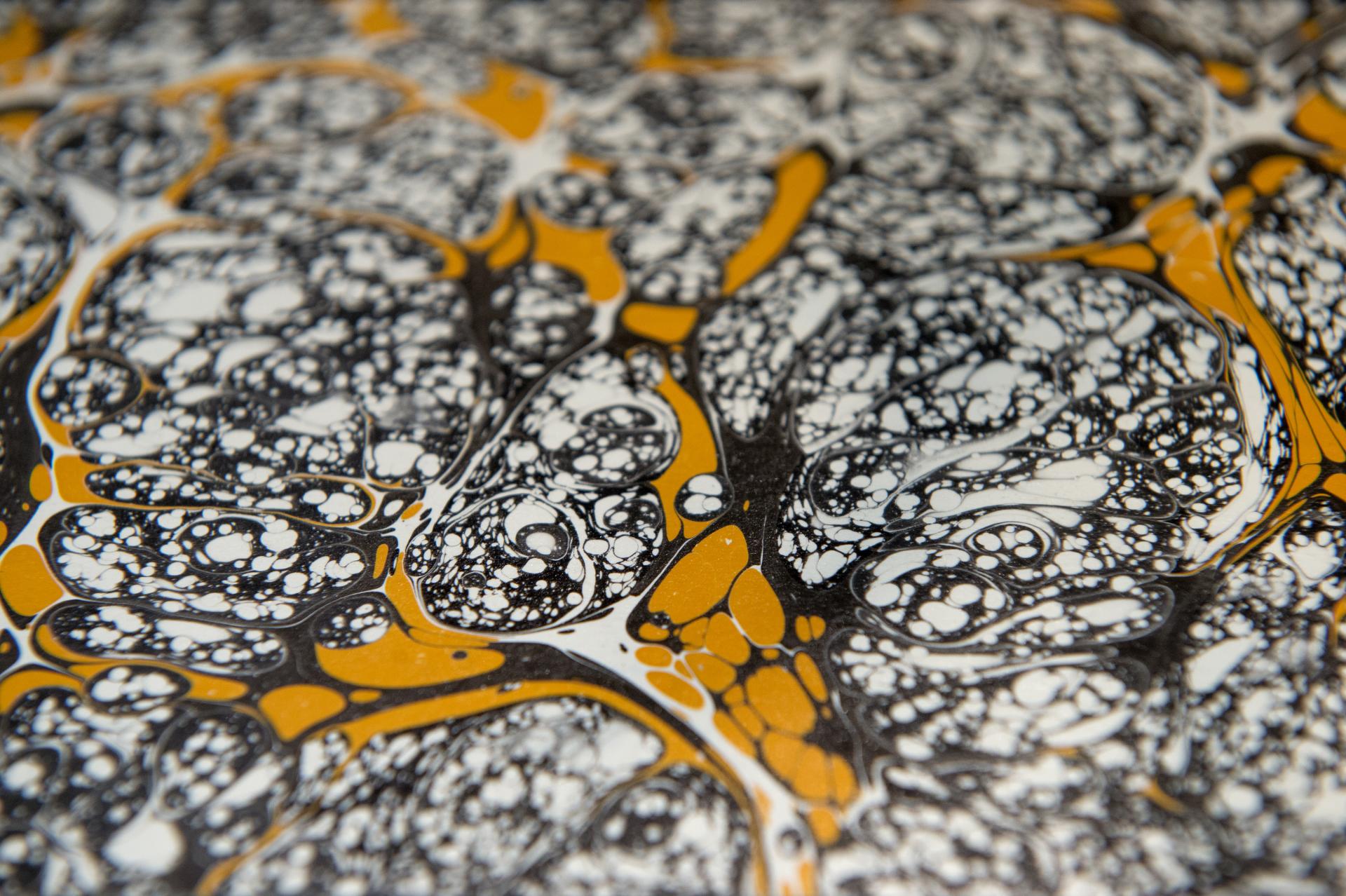Detailed close-up of a marbled surface featuring intricate black, white, and vibrant orange patterns at the Surface Design Show 2020.