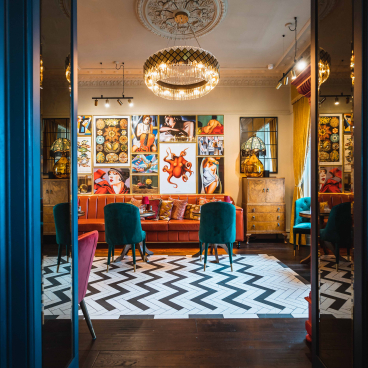 Chic interior of a boutique hotel lounge featuring vibrant artwork, stylish seating, and distinctive herringbone flooring.