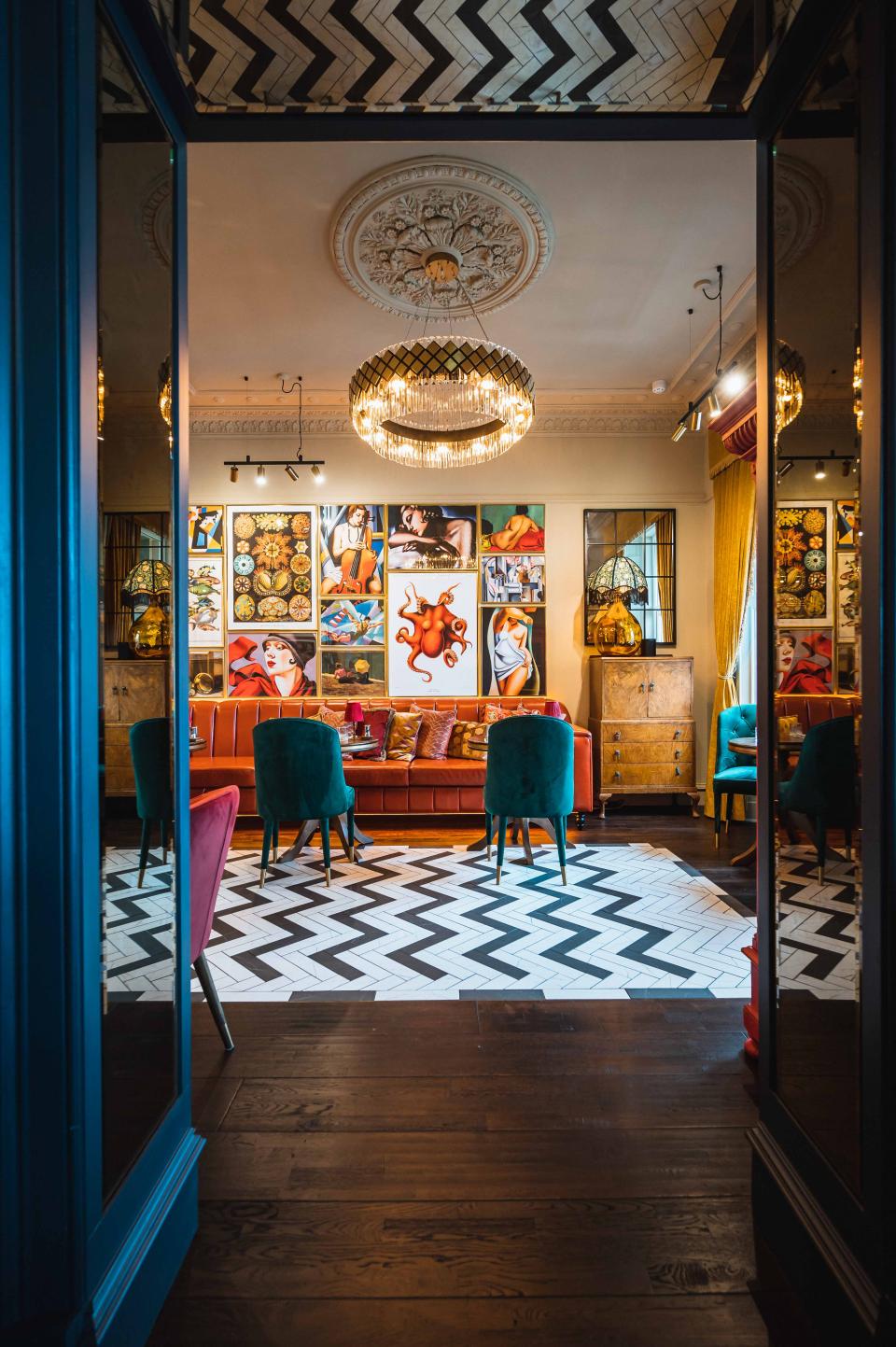 Chic interior of a boutique hotel lounge featuring vibrant artwork, stylish seating, and distinctive herringbone flooring.