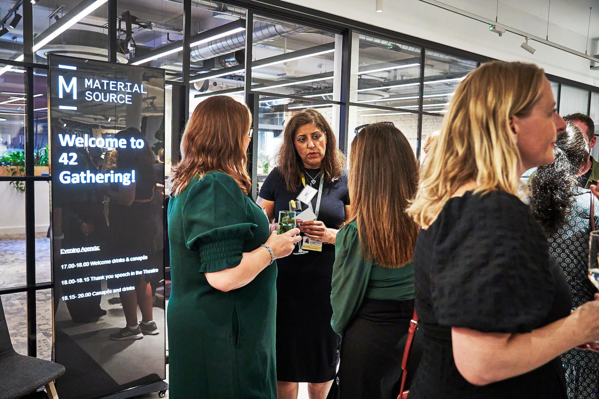 Networking attendees engage at the 42 Gathering event, with a welcome sign highlighting the podcast celebration.