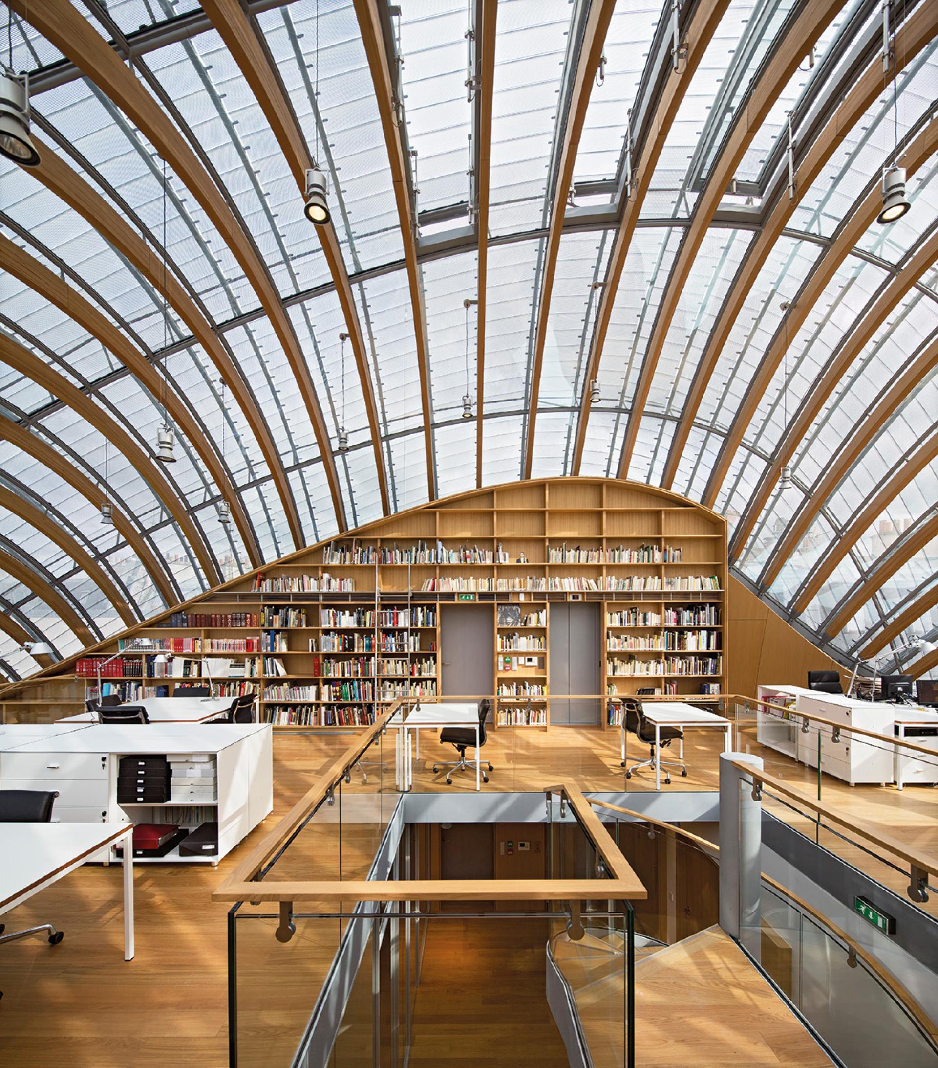 Modern library interior designed by Renzo Piano, featuring wooden arches, natural light, and bookshelves accentuating architectural innovation.