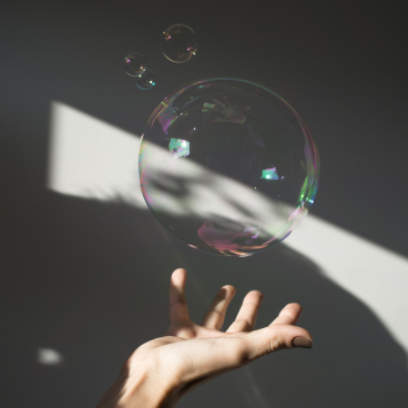 A hand reaching out to a large bubble reflecting light, showcasing the art of light and design.