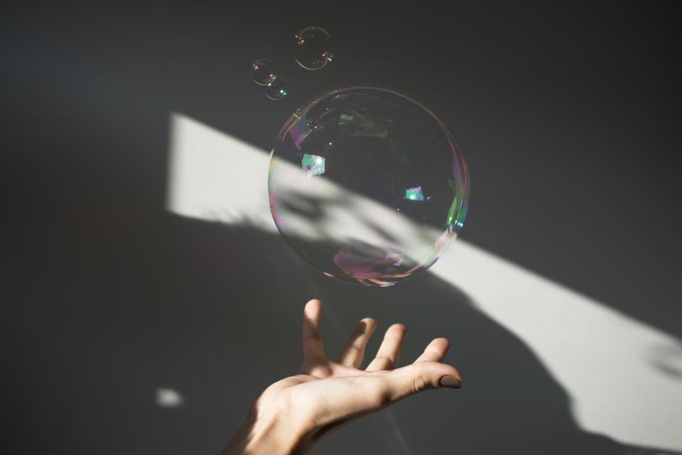 A hand reaching out to a large bubble reflecting light, showcasing the art of light and design.