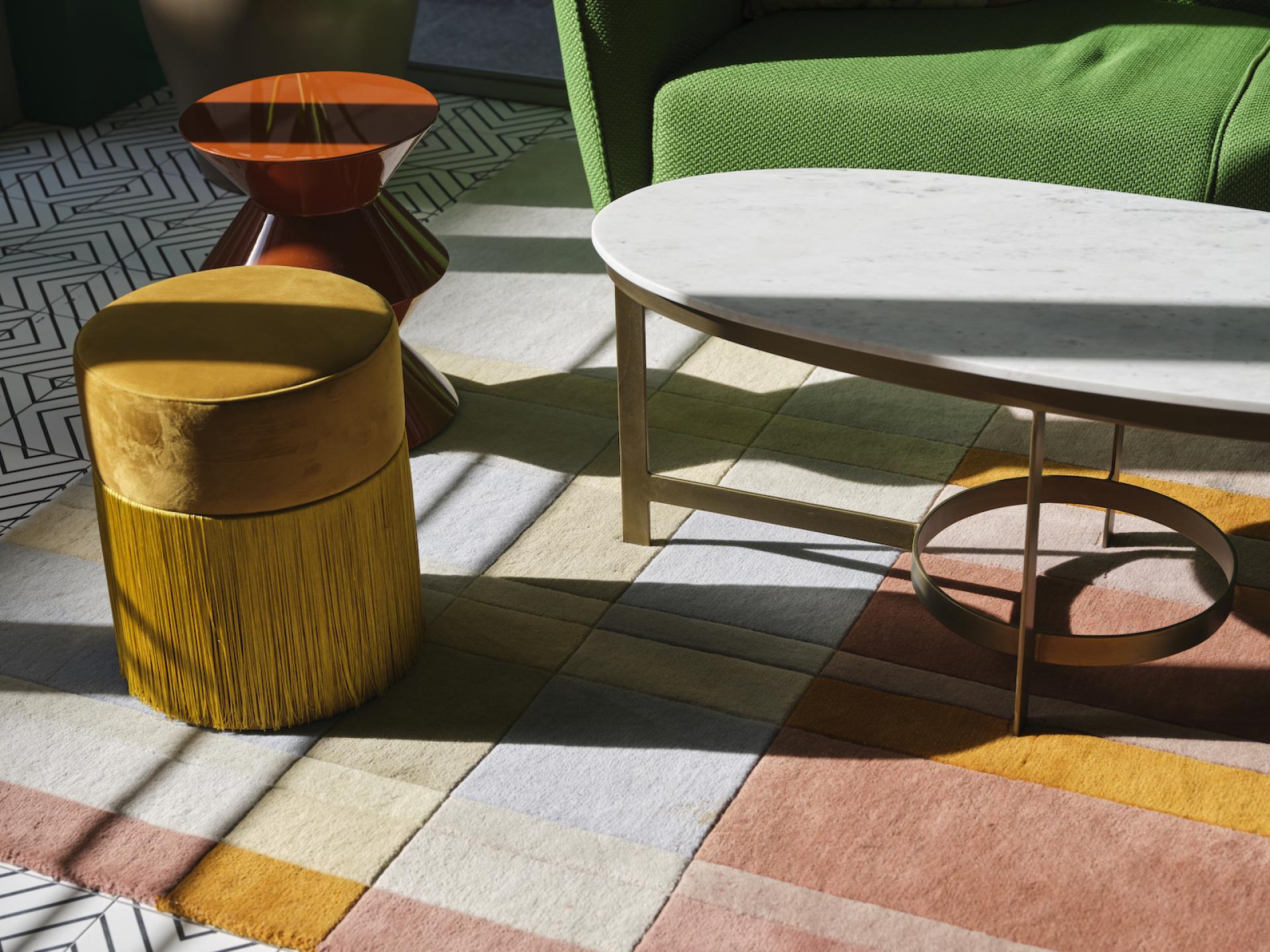 Vibrant furniture and colorful rugs create a stylish interior design in Naumi Studio Hotel, showcasing modern color blocking and eclectic decor.