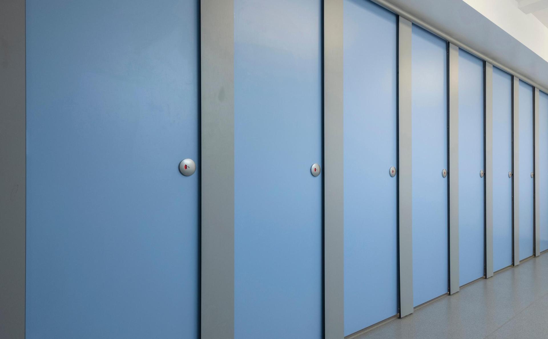 Rows of gender-neutral washroom doors in a modern design, highlighting accessibility in educational spaces.