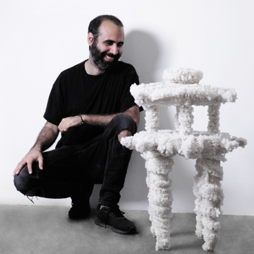 Innovative vegan furniture made from mineral materials, featuring a man proudly displaying a unique, sculptural design.