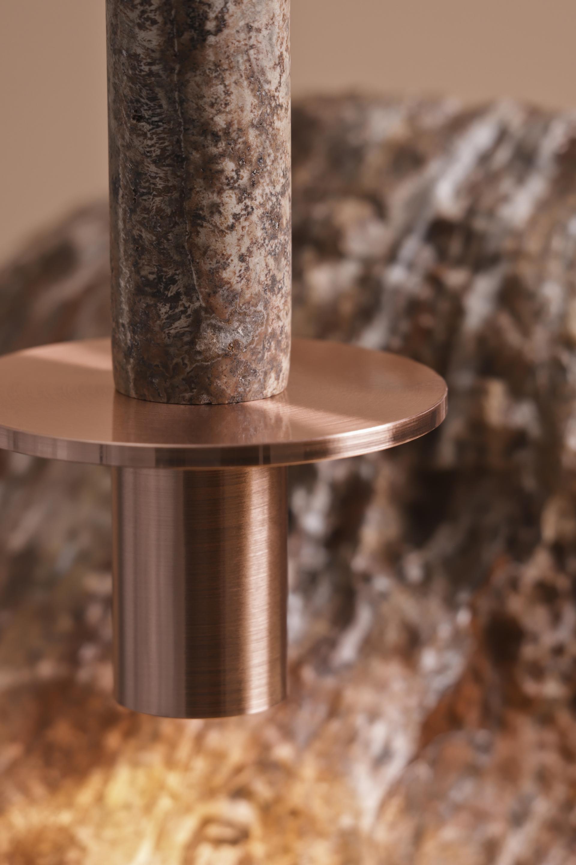 Close-up of Meta collection lamp showcasing a textured stone pole and elegant copper base, highlighting innovative design finishes.