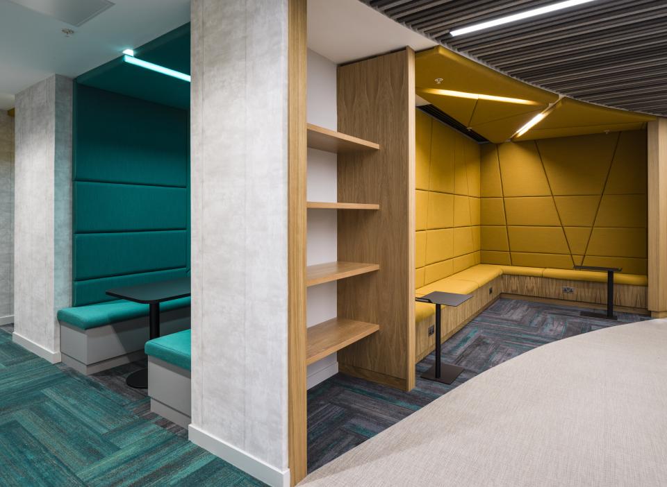 Modern office interior design featuring vibrant teal and yellow seating areas, highlighting the WELL certified workspace initiative.