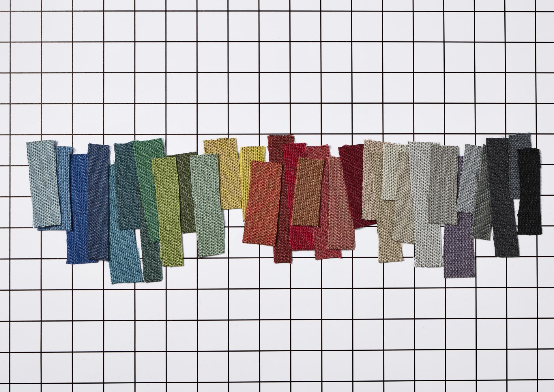Colorful fabric swatches displayed on a grid background, showcasing Camira's eco-friendly RePlay textile range.