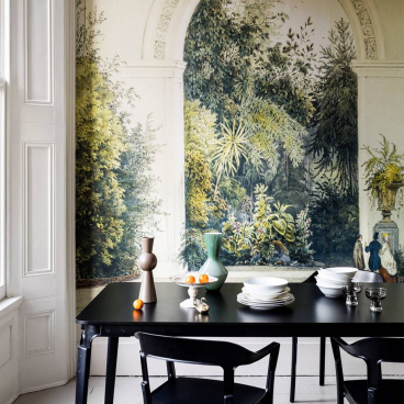 Elegant dining table set against a botanical mural, featuring decorative vases and plates, enhancing a green-themed ambience.