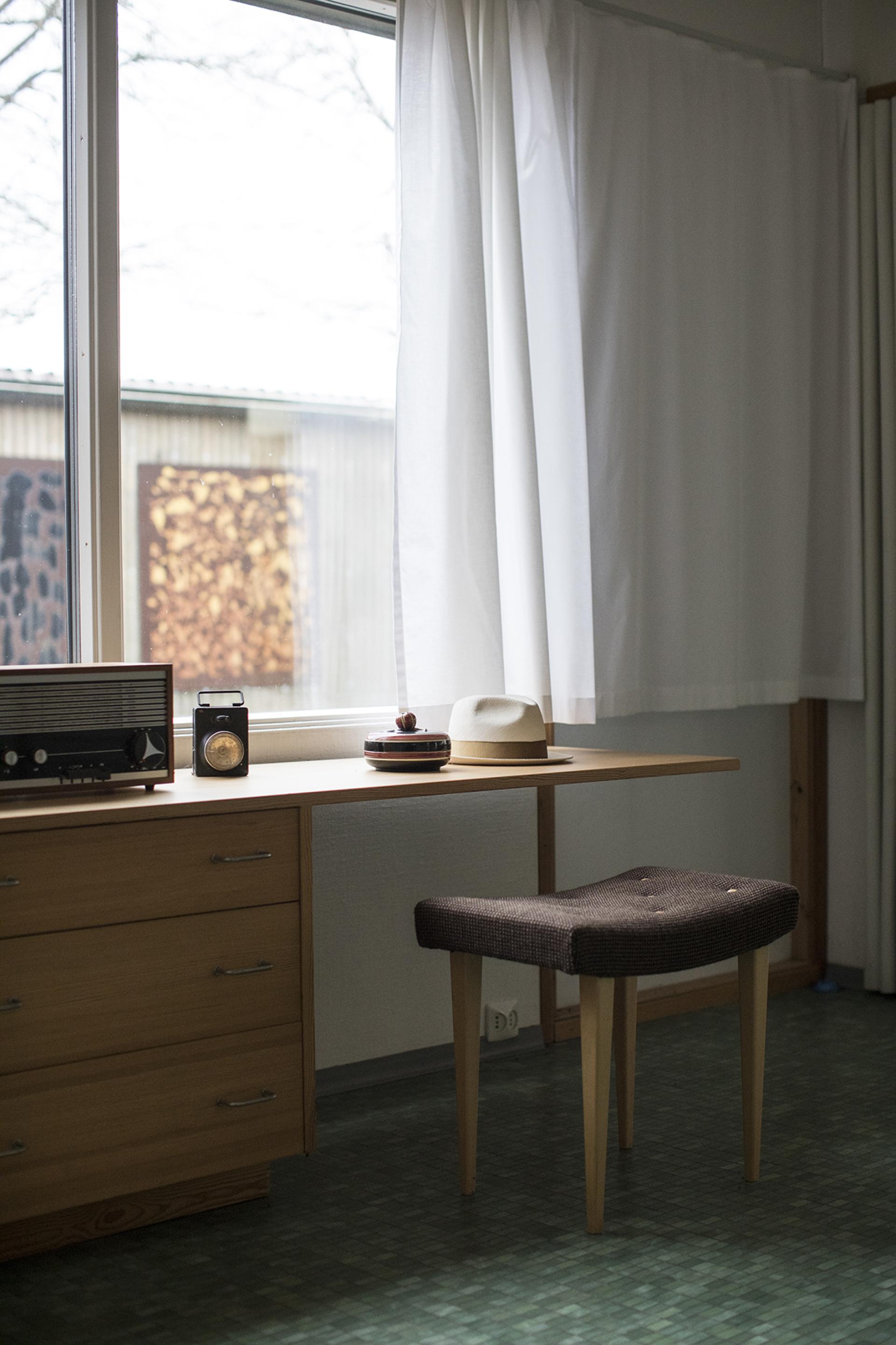 Vintage desk with a radio, stool, and decorative items in the preserved home of Bruno Mathsson, Södra Kull, Tånnö.