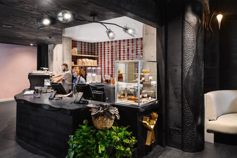 Modern hotel lobby with dark wood finishes, a coffee counter, and natural plant accents in Austin, Texas.
