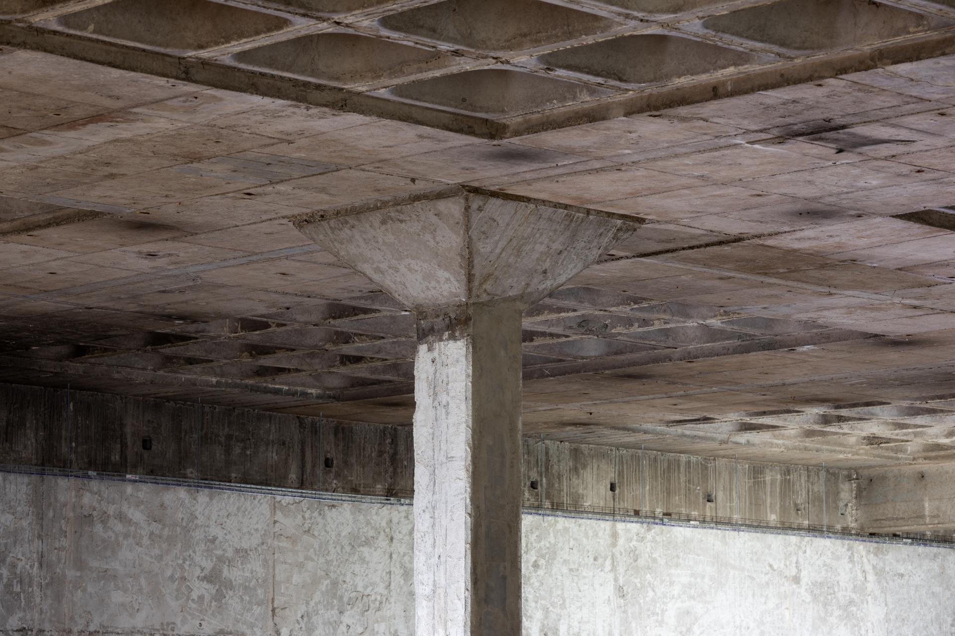 Empty concrete interior showcasing exposed structural elements of a venue, emphasizing the transformation of New Century.