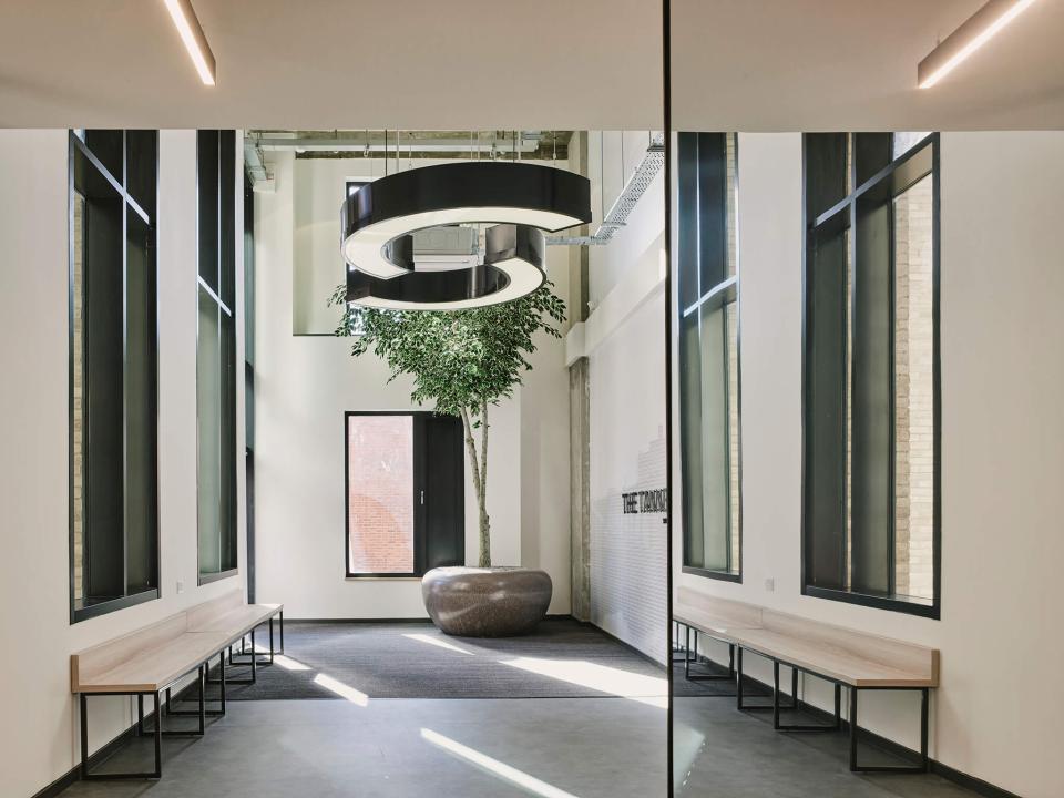 Contemporary lobby of The Tannery, featuring sleek benches, a large light fixture, and indoor plants in Leicester.