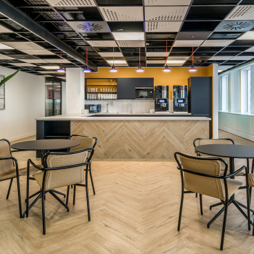 Modern office kitchen space featuring stylish seating, countertops, and appliances in central London office design.