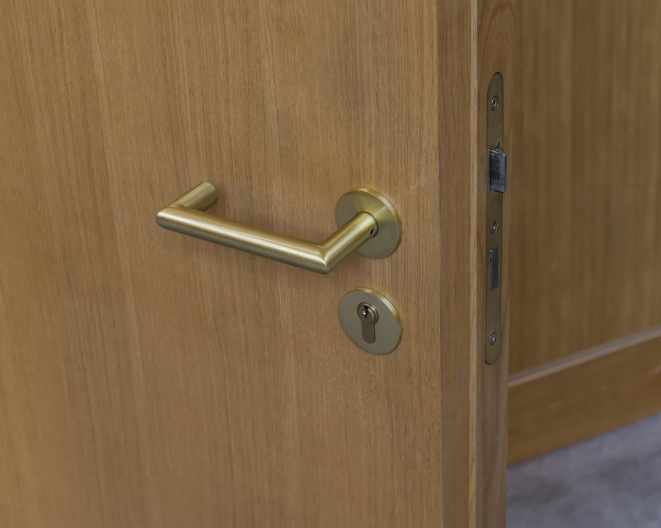 Brass door handle on a wooden door, exemplifying the Cambridge Central Mosque's blend of traditional and modern design.