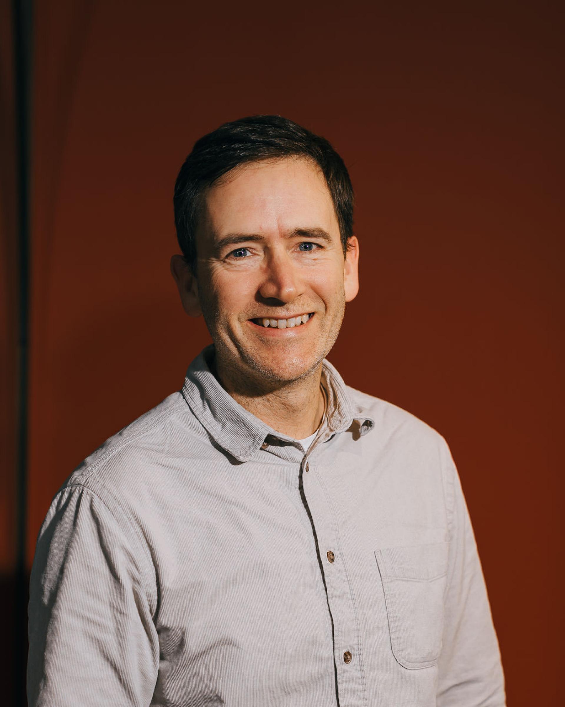 Smiling man in a casual shirt, promoting discussions on sustainability in the context of biomaterials.