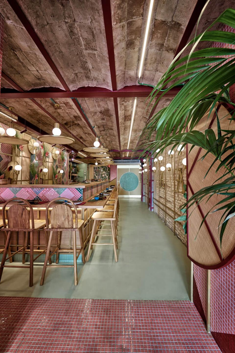 Modern tropical sushi restaurant interior featuring vibrant decor, wooden seating, and lush greenery designed by Masquespacio in Valencia.