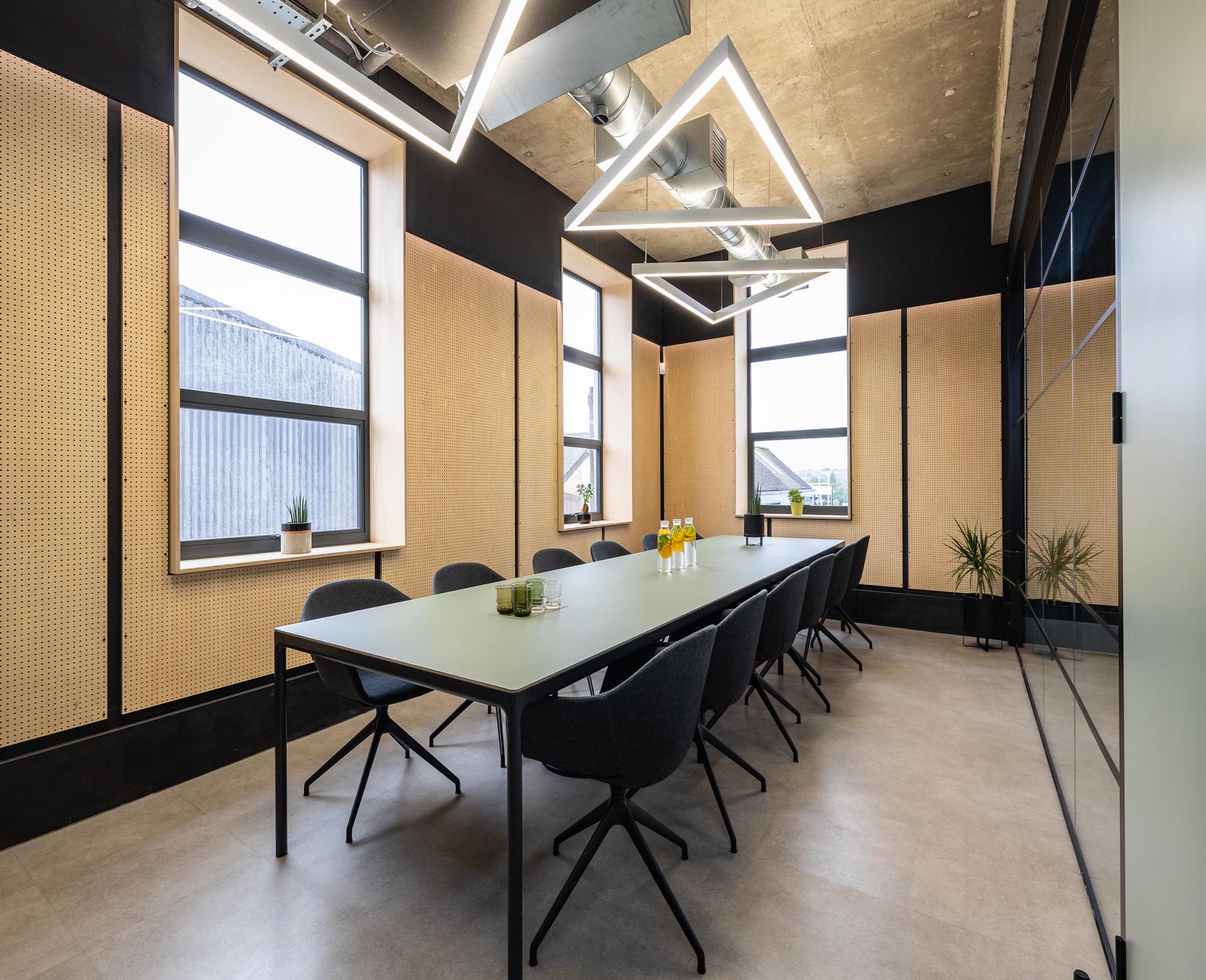 Modern conference room featuring a long table, stylish chairs, large windows, and contemporary lighting design.