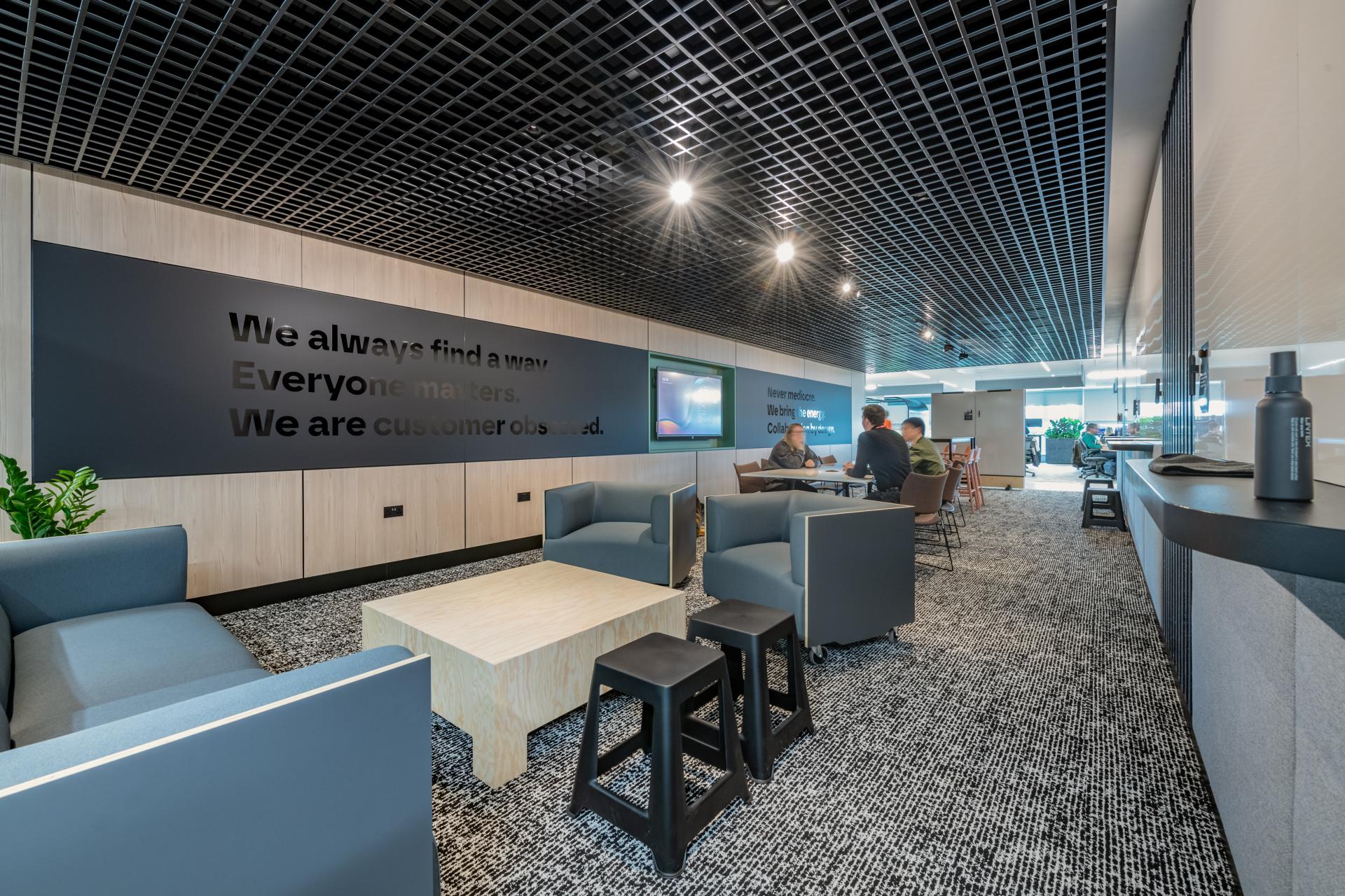 Modern office space designed for collaboration, featuring comfortable seating and motivational wall text for FinTech company Conferma.