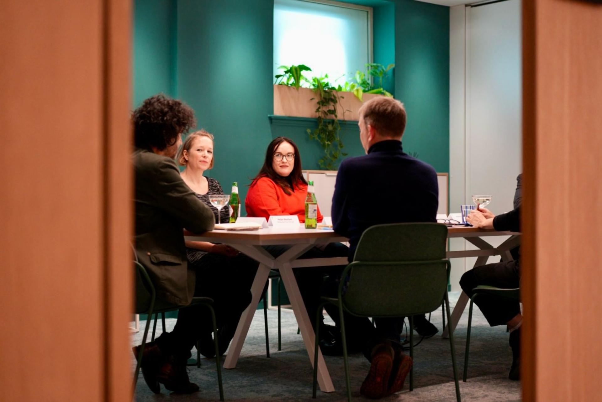 A diverse group of professionals engaged in a collaborative discussion at a modern workplace meeting.