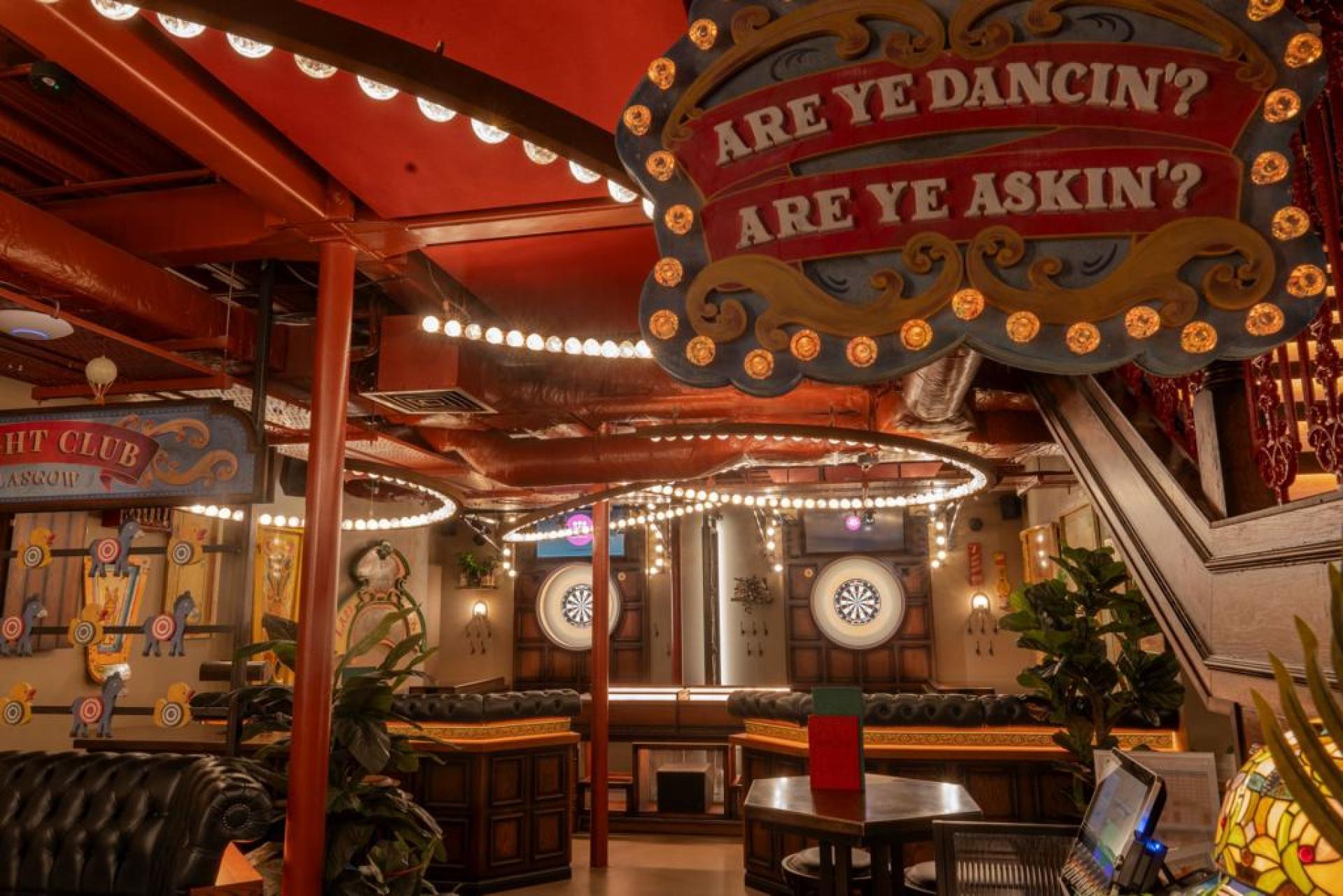 Vibrant interior of a lively venue featuring dartboards, plush seating, and decorative lighting promoting social interaction and well-being.