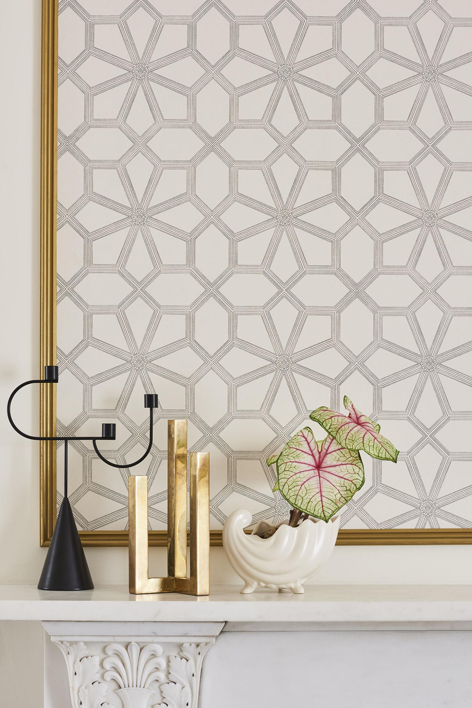Stylish mantel featuring Cole & Son wallpaper, decorative vases, and a vibrant plant, showcasing British heritage design elements.