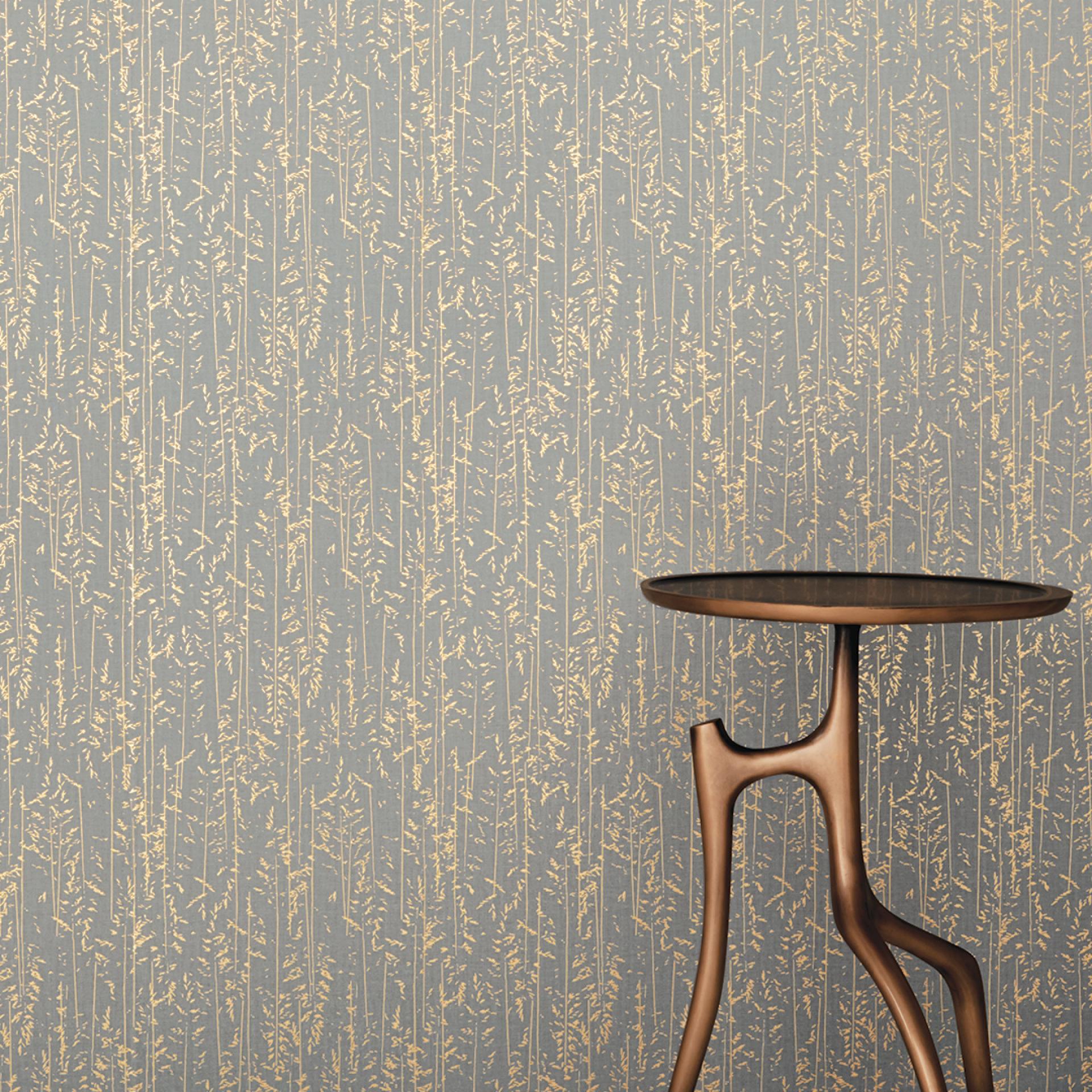 Elegant wallcovering design by HOLLY HUNT features a soft blue background with intricate gold foliage patterns, complemented by a modern table.
