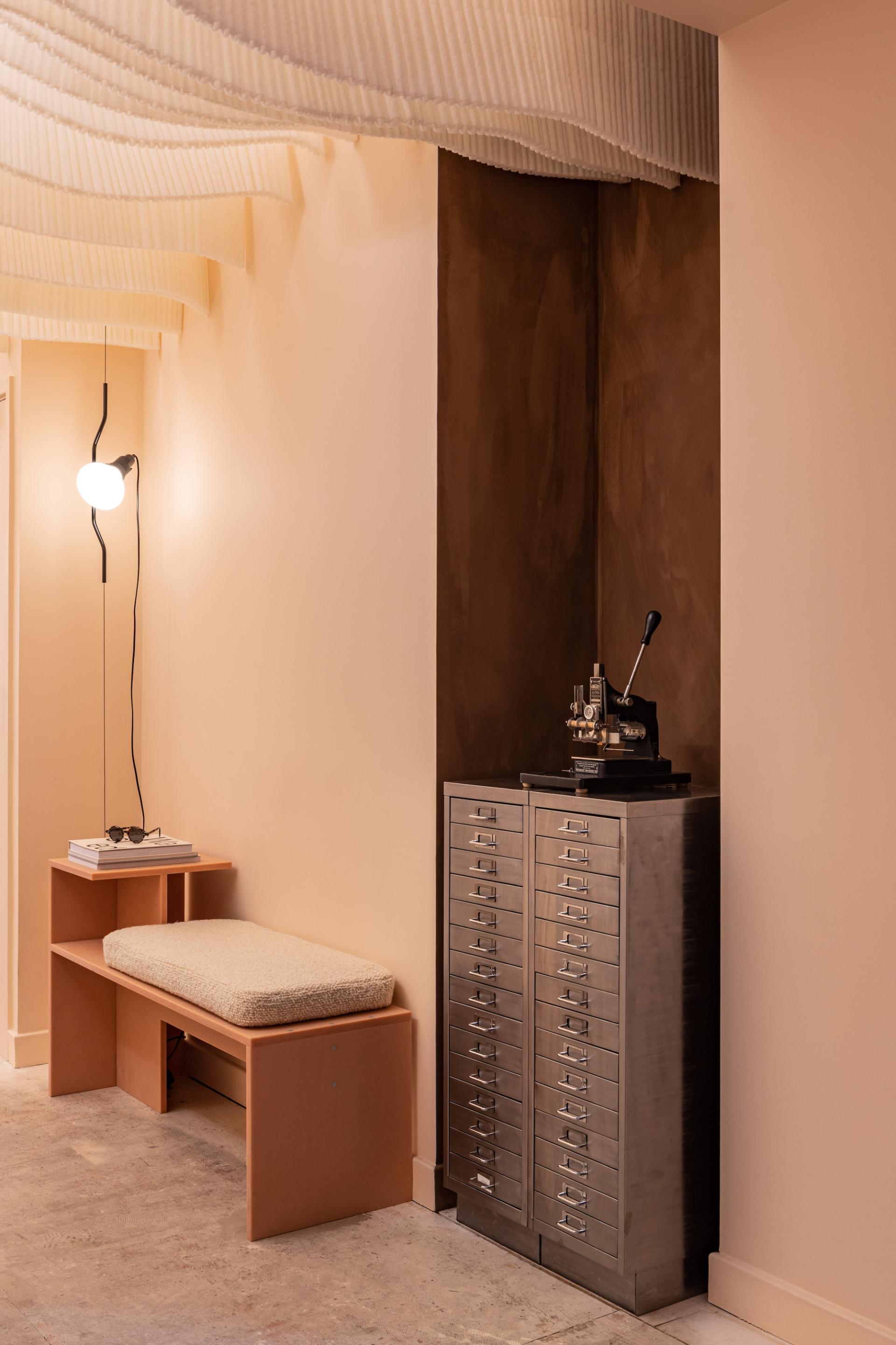 Stylish interior of a zero-waste eyewear store featuring a bench, storage unit, and modern lighting.