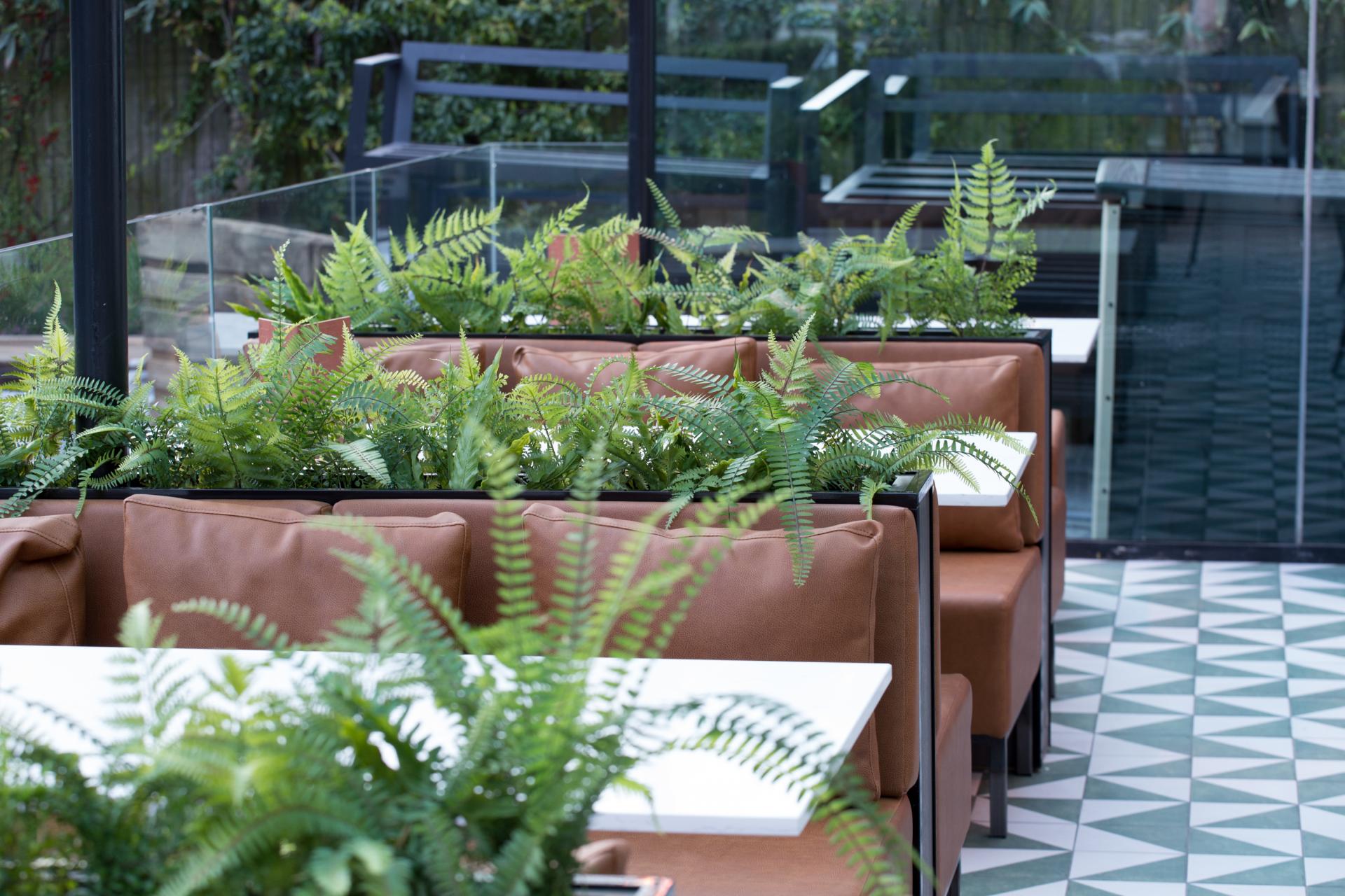 Stylish interior of Albert's Didsbury featuring cozy booths and lush ferns, highlighting SpaceInvader's design expertise.