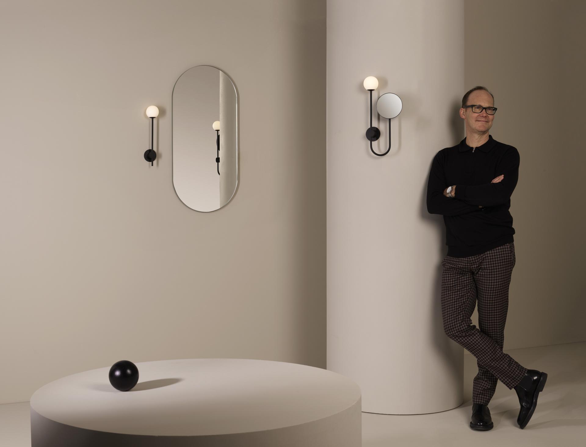 Contemporary lighting designs showcased, featuring a sleek wall sconce, mirror, and a designer near minimalistic furnishings.