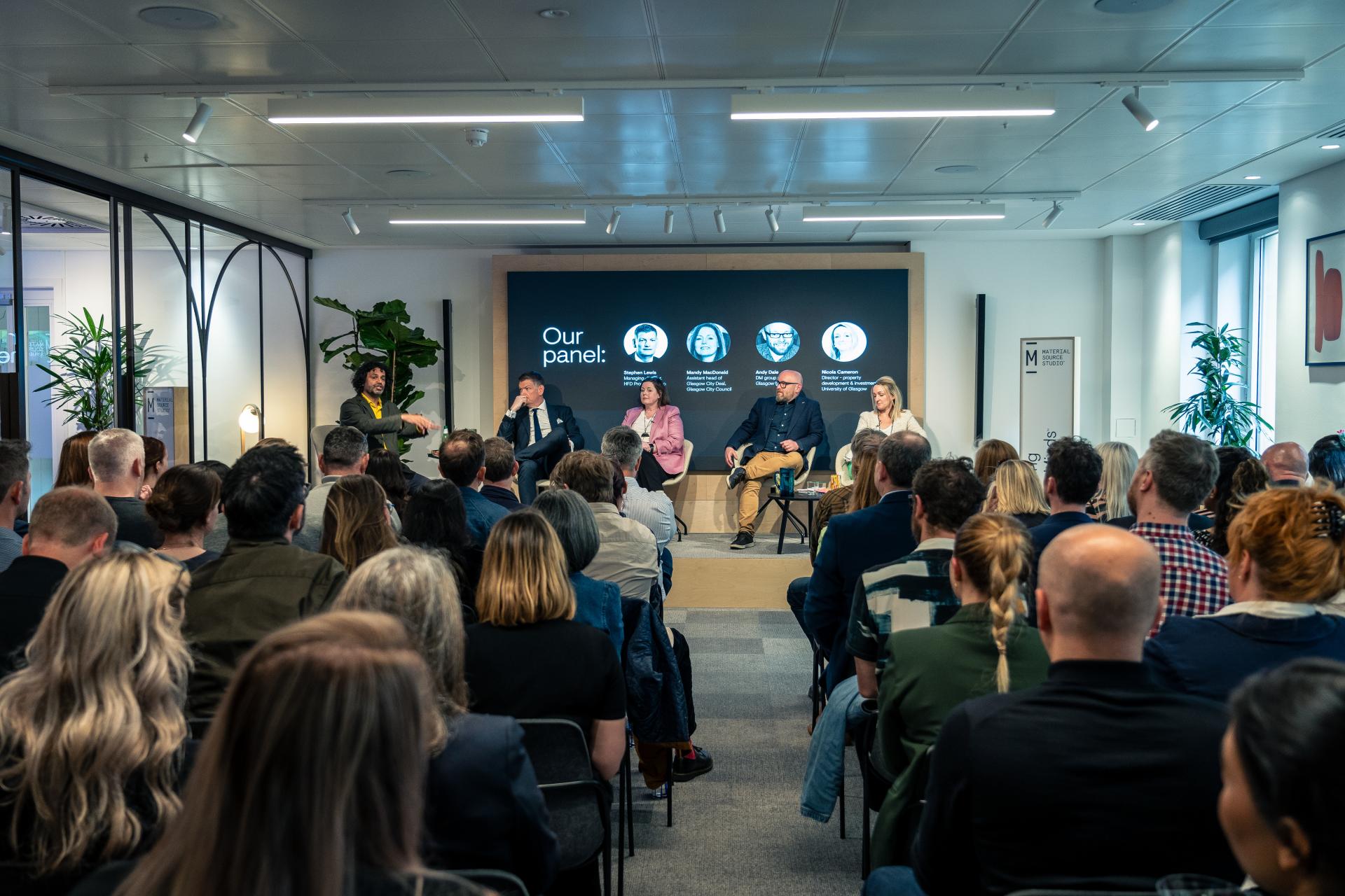 Panel discussion on Glasgow's property outlook with attendees engaged in a modern venue, featuring industry experts sharing insights.